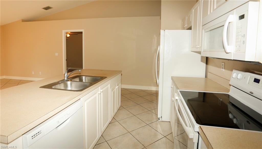 Kitchen featuring a central island with a double basin sink, white cabinetry, and a built-in dishwasher