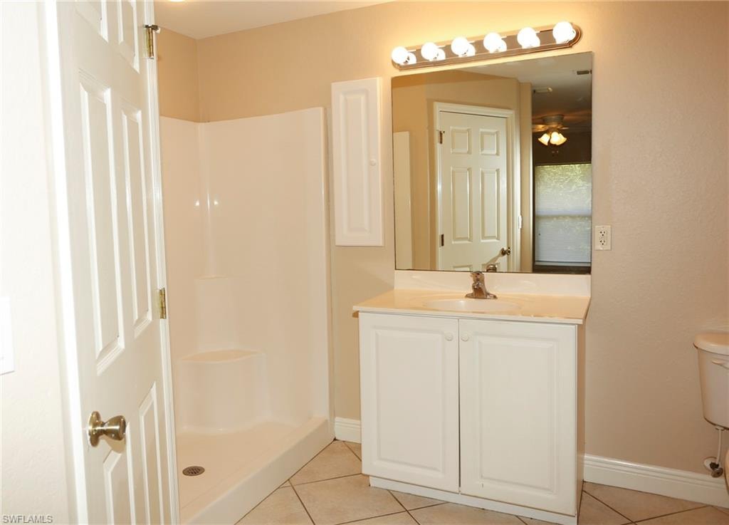 Bathroom featuring a white vanity with a light-colored countertop, an integrated sink, and a large mirror
