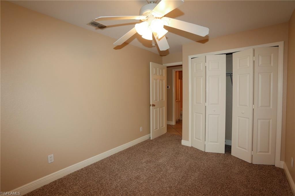 Interior room featuring neutral-toned walls, brown carpet flooring, and white baseboards
