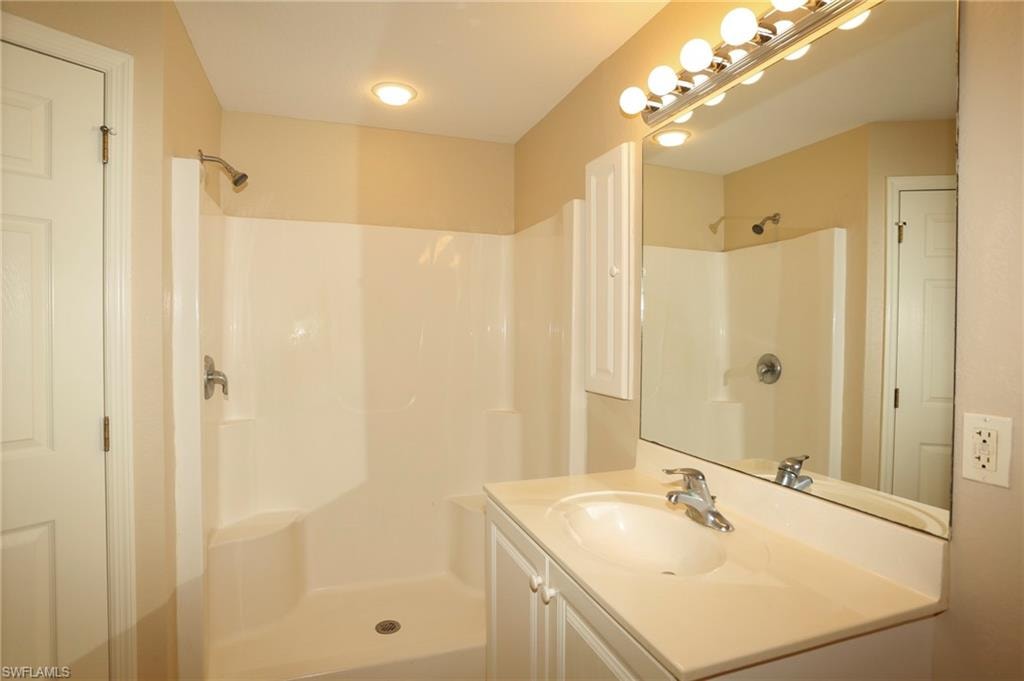 Bathroom featuring a single vanity with an integrated sink, a large mirror, and a chrome light fixture
