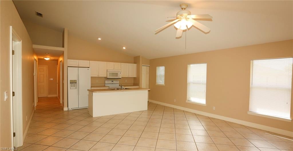 Open-concept living area featuring vaulted ceilings, diagonal tile flooring, and a ceiling fan