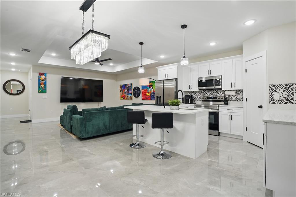 Kitchen featuring stainless steel appliances, light marble finish floors, backsplash, baseboards, and recessed lighting