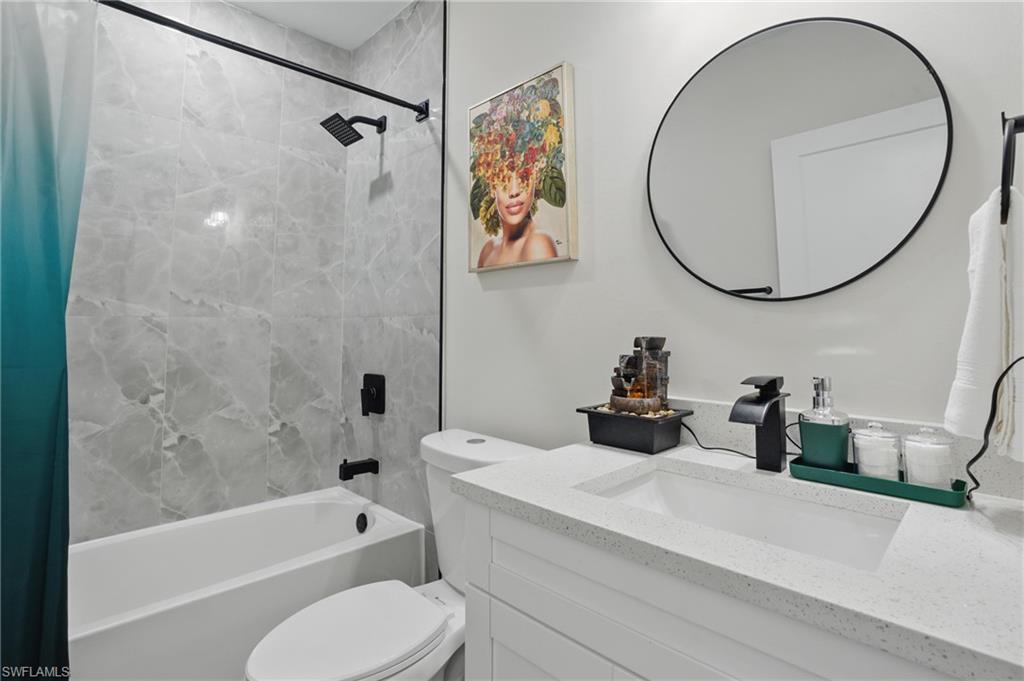 Bathroom with shower / bathtub combination with curtain, toilet, and vanity