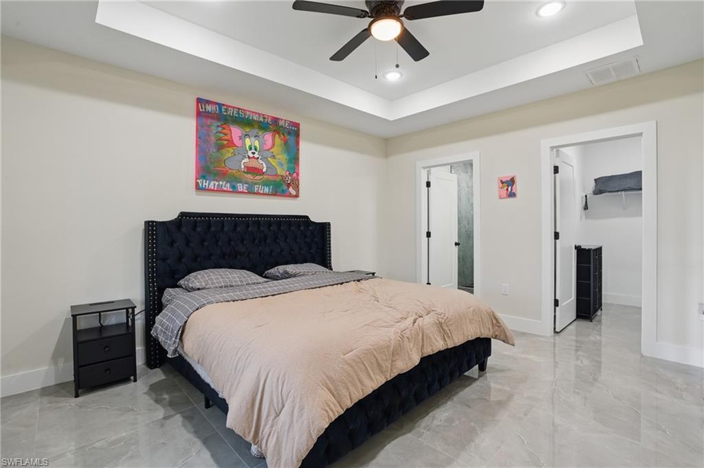 Bedroom with a tray ceiling, baseboards, light marble finish flooring, and recessed lighting