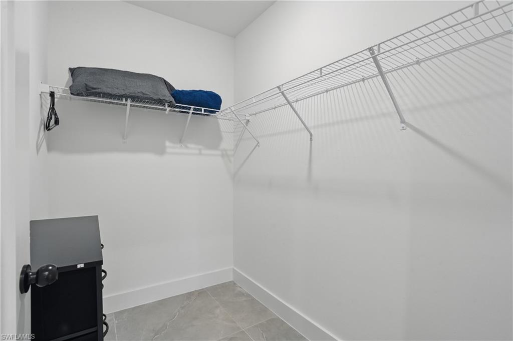 Spacious closet featuring light marble finish floors