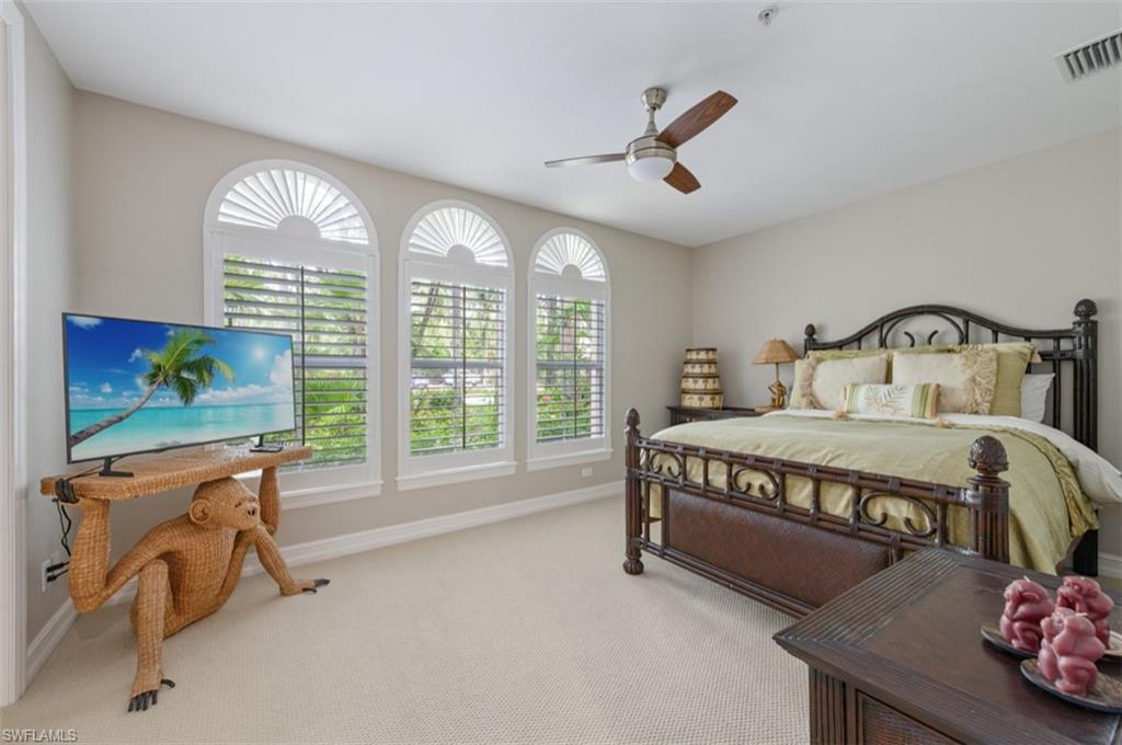 Carpeted bedroom with multiple windows and ceiling fan