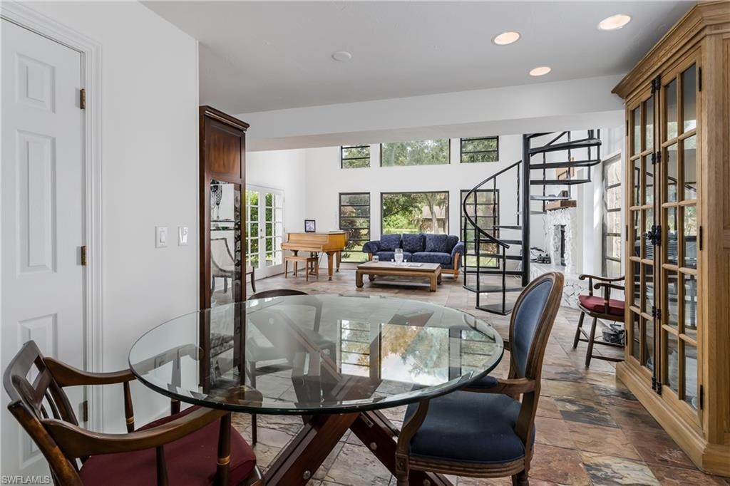 Spacious living area featuring stone flooring, a spiral staircase, and extensive window placements