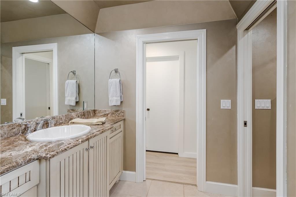 Bathroom vanity featuring a single undermount sink, stone countertop, and slatted cabinet doors