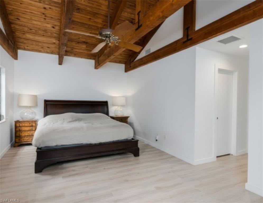 Exposed wood beam ceiling with a ceiling fan, light wood-finish flooring, white painted walls, and a recessed ceiling light fixture