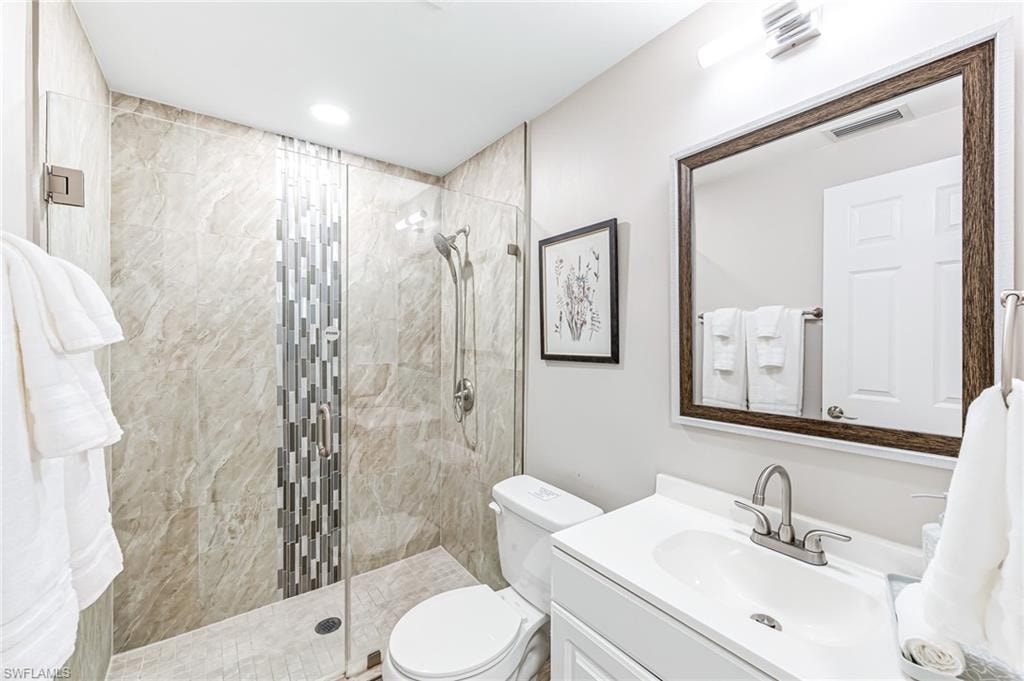 Bathroom featuring a tile shower, vanity, and toilet