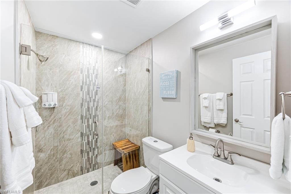 Bathroom featuring vanity, toilet, and a shower with door