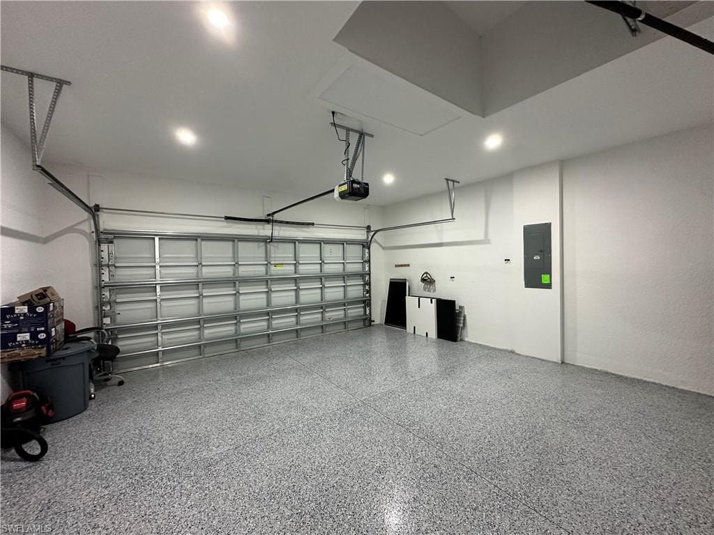 Spacious garage featuring a durable epoxy speckled floor, recessed lighting, an automatic garage door opener, and an access panel