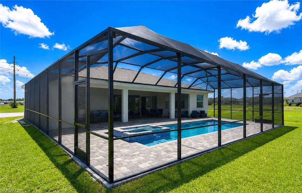 Expansive screened lanai with aluminum frame structure featuring full-length glass panels, concrete paver decking, and integrated swimming pool with surrounding manicured lawn