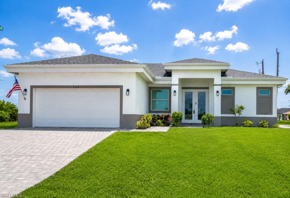 Contemporary stucco exterior featuring a two-car garage, paved driveway, and double-door entry