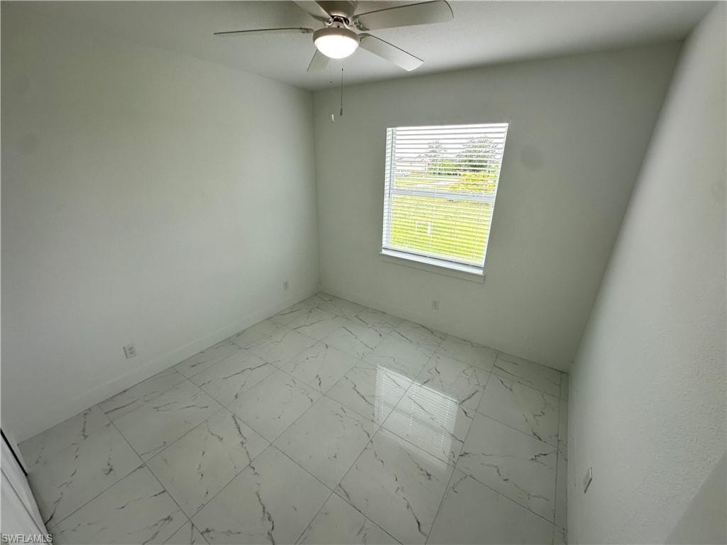 Room featuring a ceiling fan with integrated lighting, large window with blinds, and white square floor tiles with grey veining