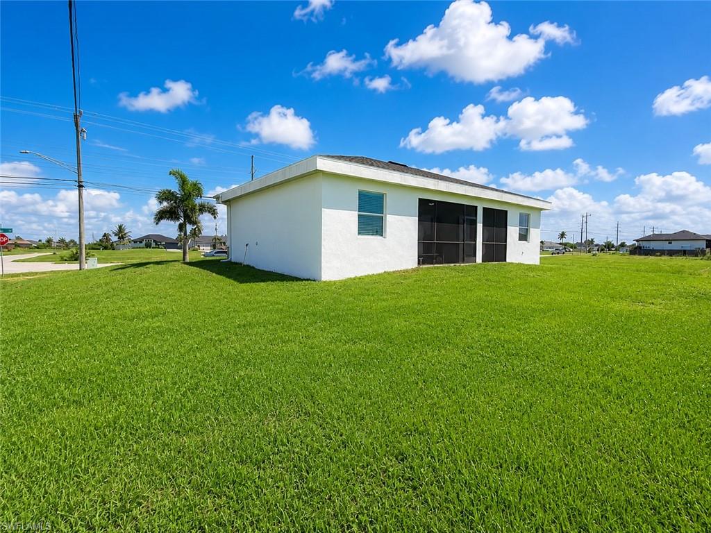 Expansive green lawn surrounds a white stucco residence with multiple windows and a screened lanai