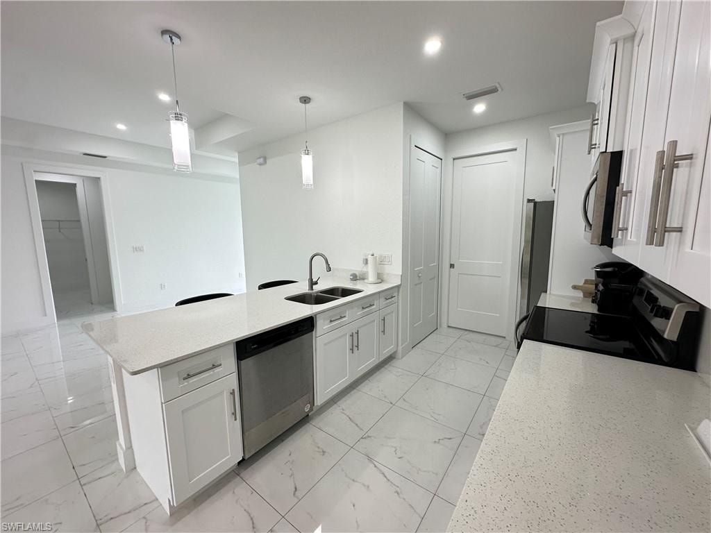 Kitchen featuring white shaker cabinetry, stainless steel appliances, and light-toned quartz countertops