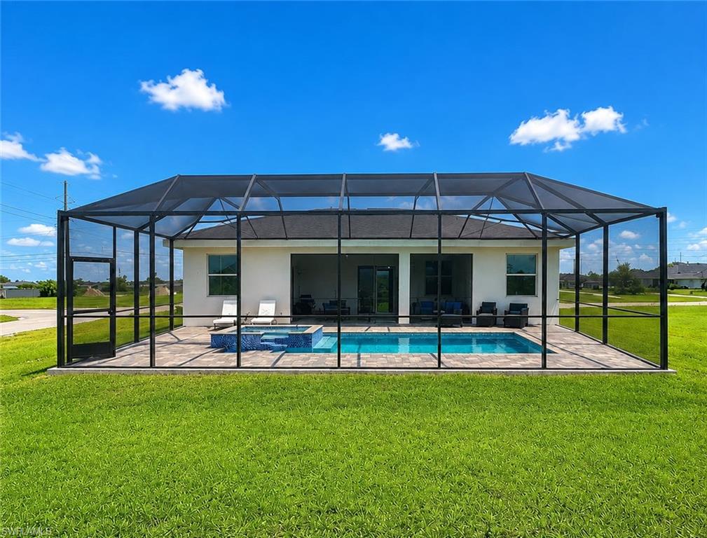 Screened-in outdoor living space featuring a rectangular swimming pool, integrated hot tub, and a spacious paver deck