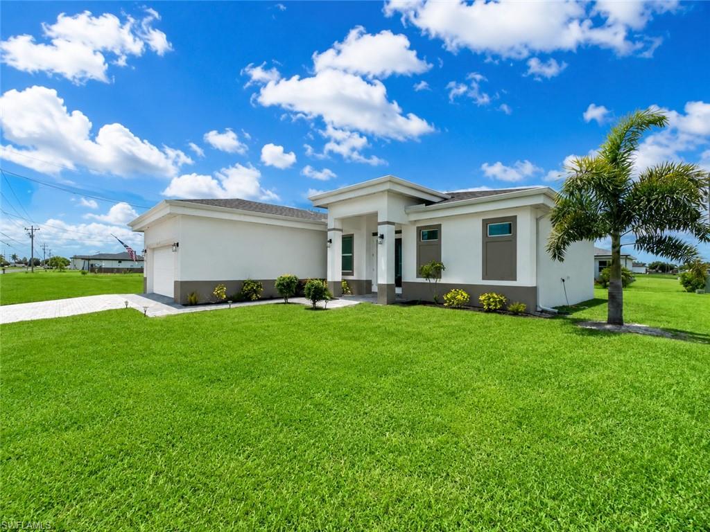 Contemporary architecture featuring a white and gray exterior, a two-car garage, and a lush green lawn