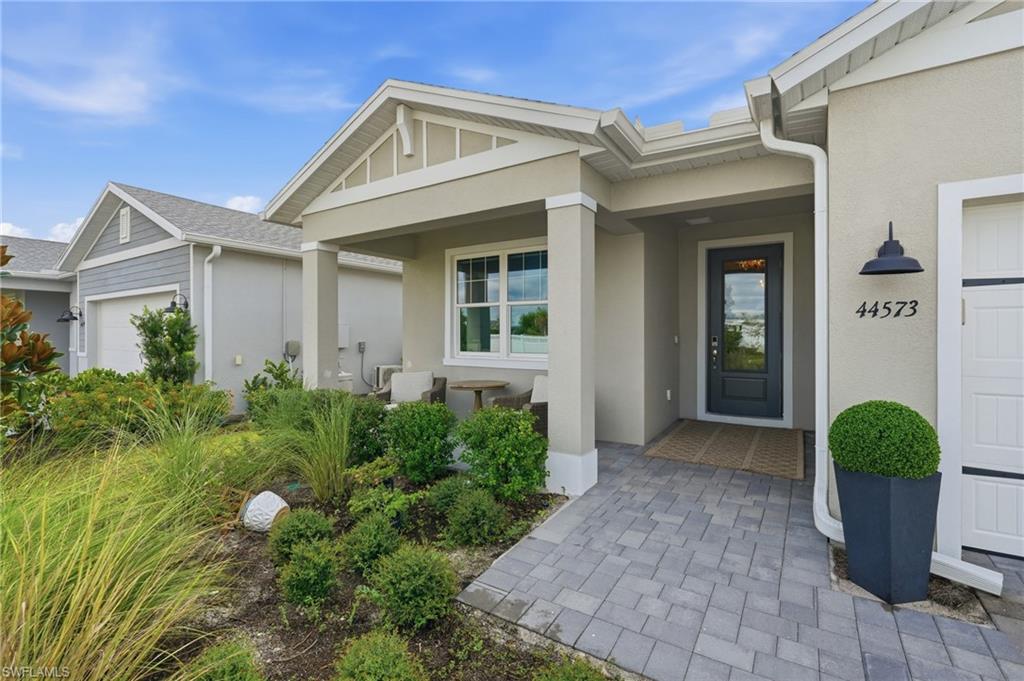Covered entry with columns, paver walkway, and a dark-paneled door with clear glass