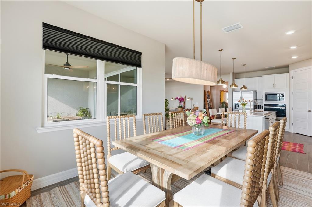 Dining area featuring a wood-finish table, an oval fabric pendant light, and a window with a black cellular shade