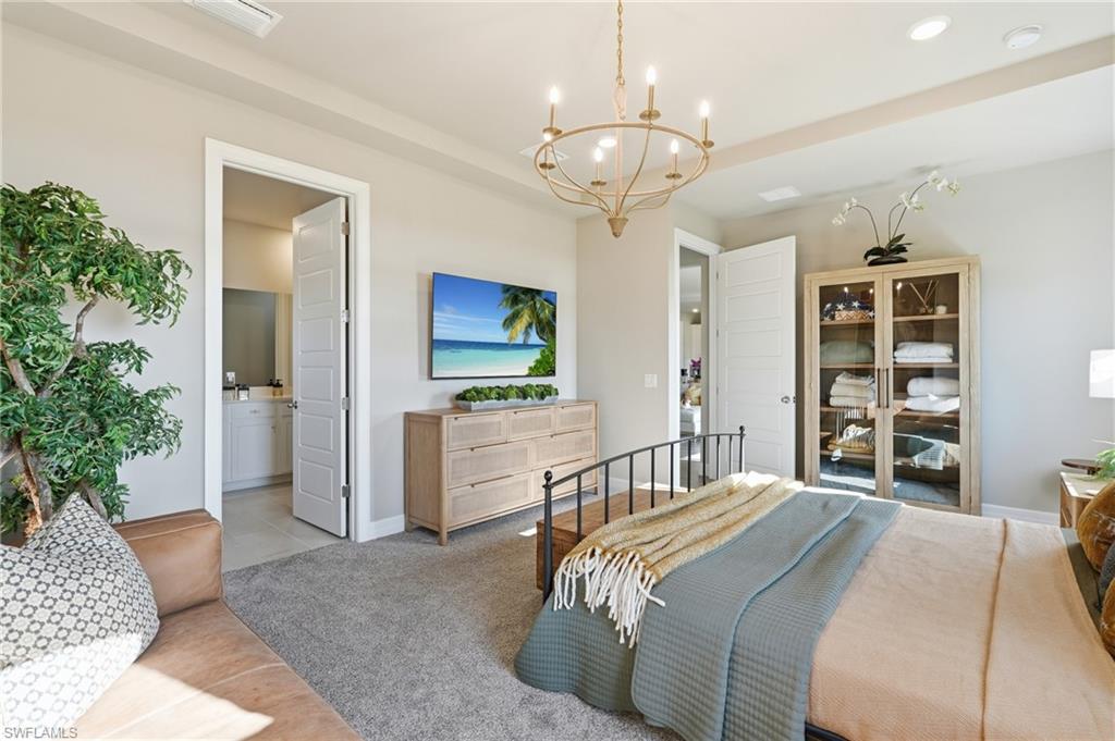 Recessed lighting, chandelier, neutral wall colors, carpeting, and a built-in vanity in the adjacent room