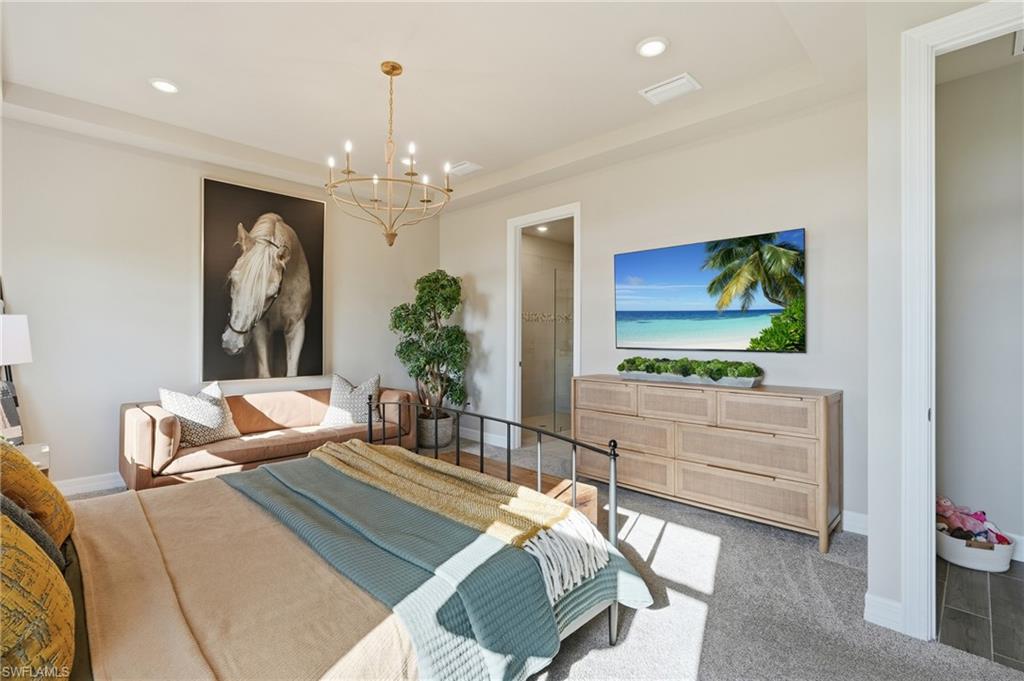 Recessed lighting, elegant chandelier, carpeting, built-in shelving, and a separate doorway