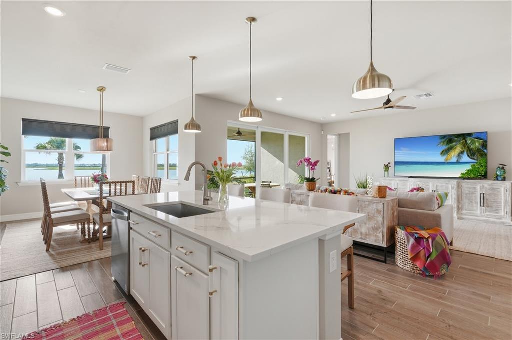 Gourmet kitchen island with an undermount sink, pendant lighting, and an integrated dishwasher
