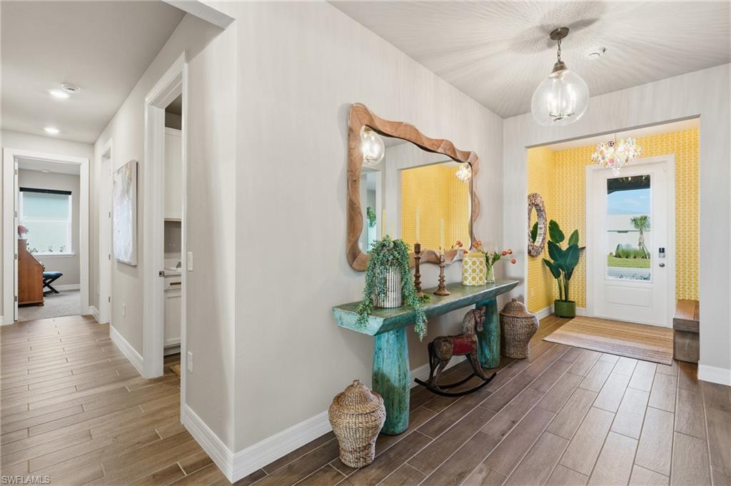 Entryway featuring wood-finish flooring, a decorative glass pendant light, and a white paneled door with glass inserts