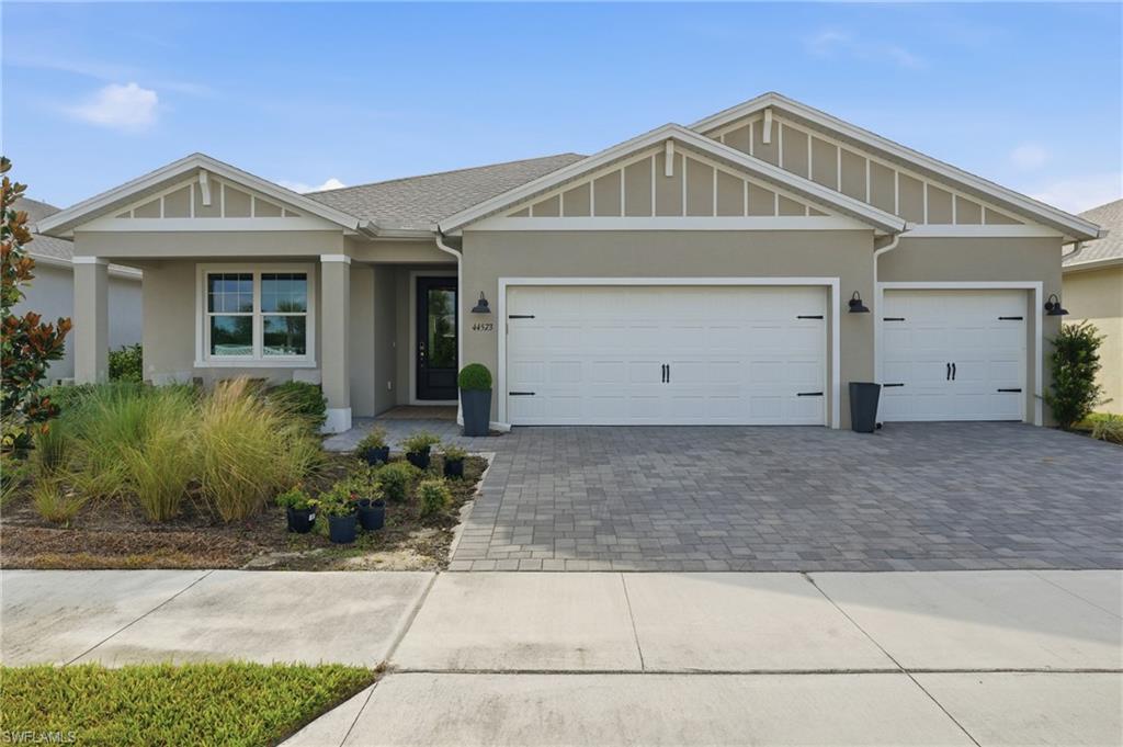 Contemporary stucco exterior with gabled roof lines, a two-car garage, a paver driveway, and an entryway with a glass-paneled front door