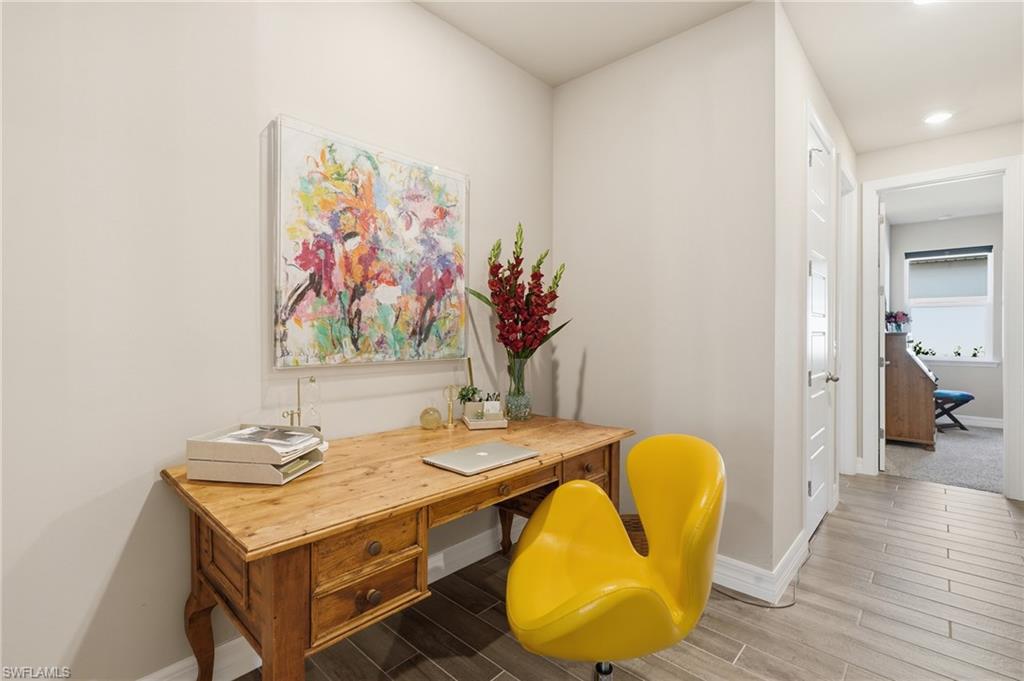 Hardwood-style tile flooring, light neutral wall color, white trim, and a white interior door