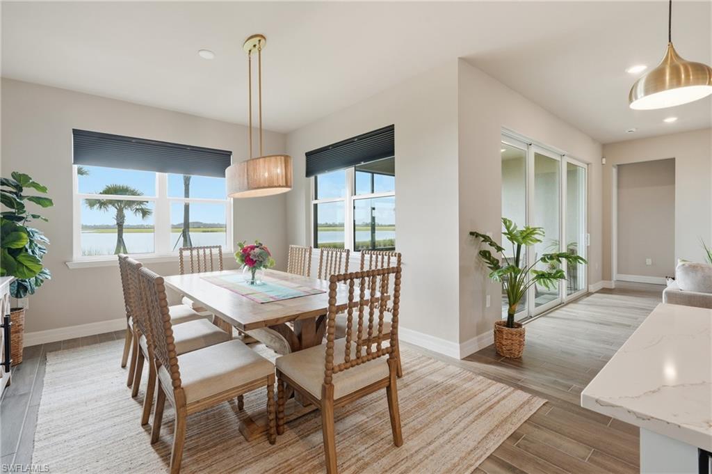 Dining area featuring a contemporary drum pendant light, wood-finish flooring, and large windows with roller shades