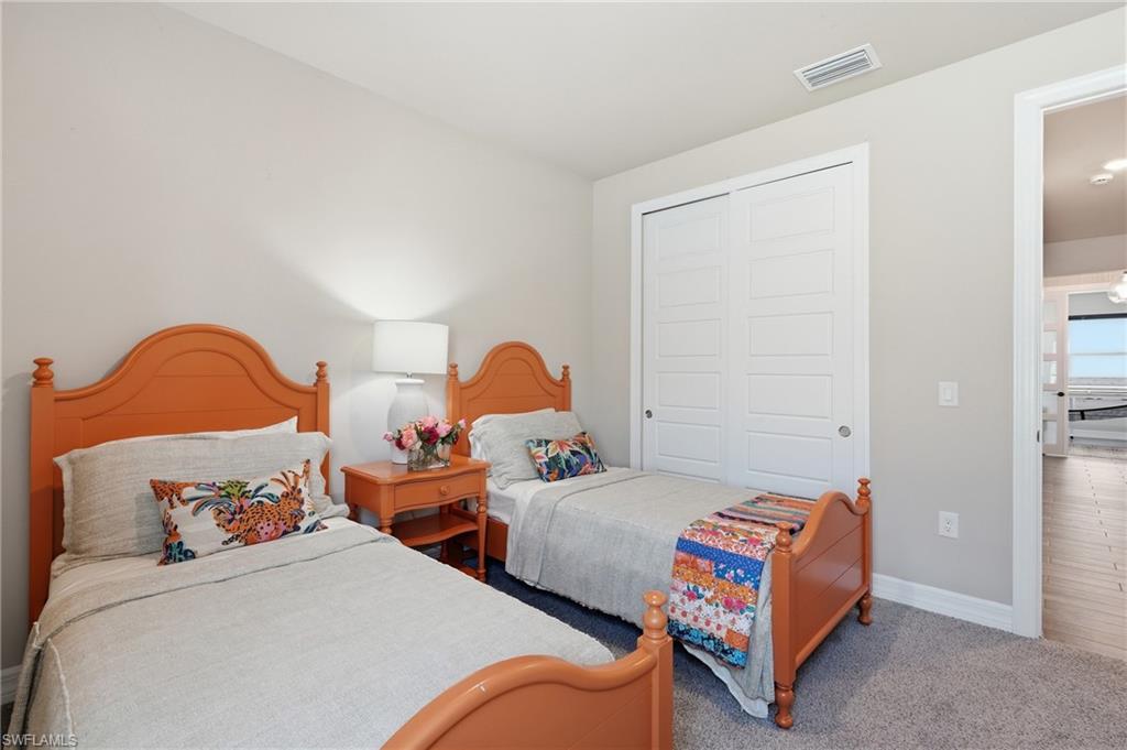 Carpeted room with light neutral walls, white sliding closet doors, and an overhead light fixture