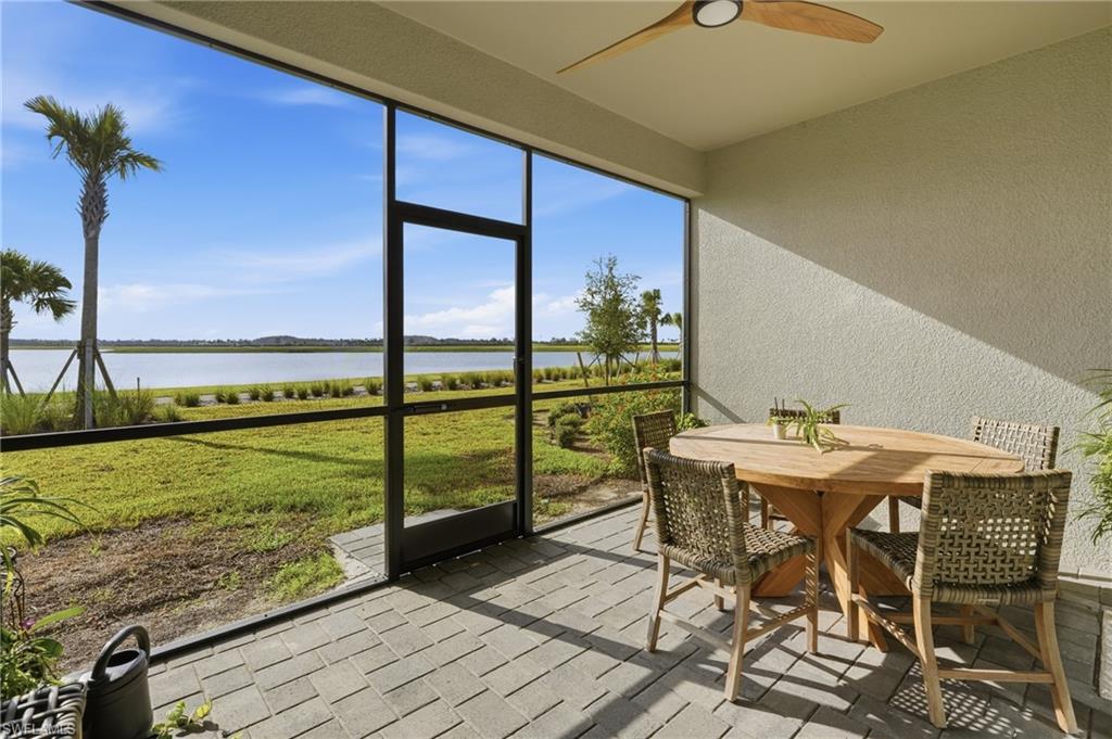 Screened-in patio with paver flooring, overhead ceiling fan, and waterfront scenery