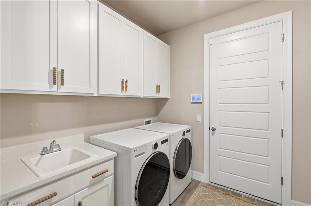 White shaker cabinetry, integrated utility sink, white paneled door, and durable flooring