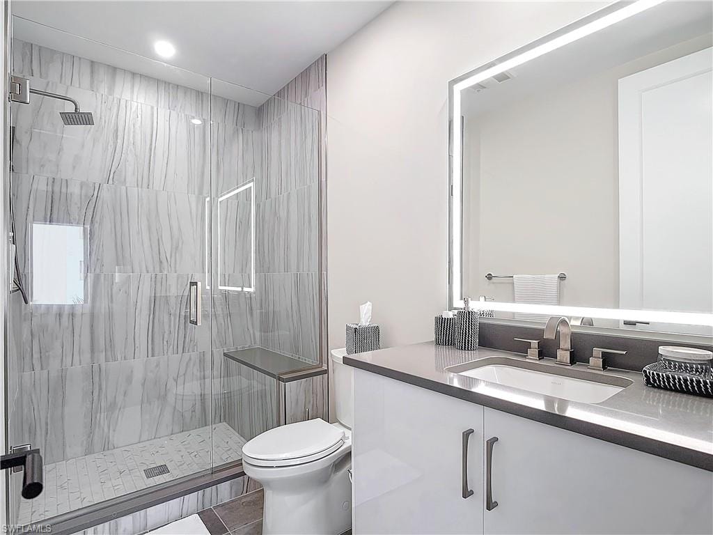 Bathroom featuring toilet, walk in shower, vanity, and tile patterned floors