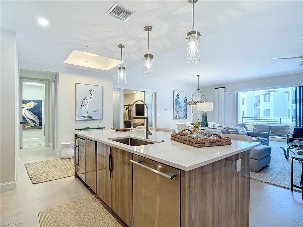 Kitchen featuring dishwasher, a kitchen island with sink, light hardwood / wood-style flooring, sink, and decorative light fixtures