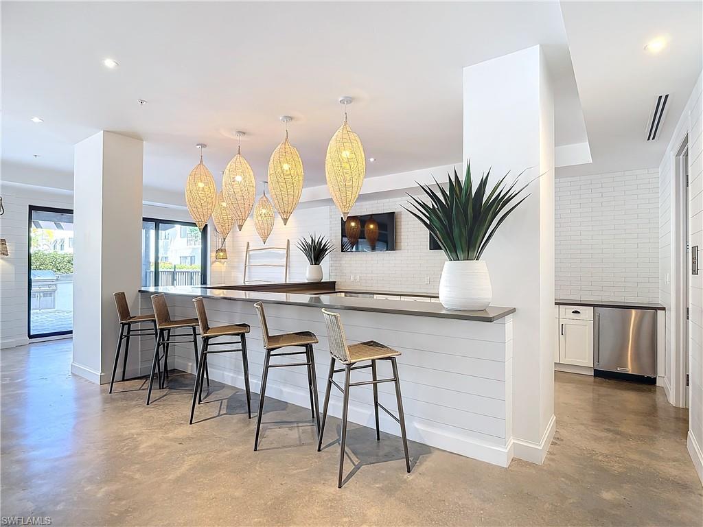 Kitchen with a breakfast bar area, backsplash, white cabinetry, dishwasher, and pendant lighting