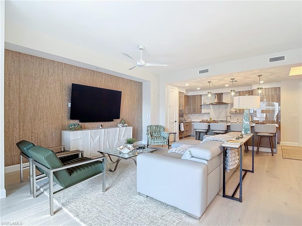 Living room with wood walls, light hardwood / wood-style floors, and ceiling fan