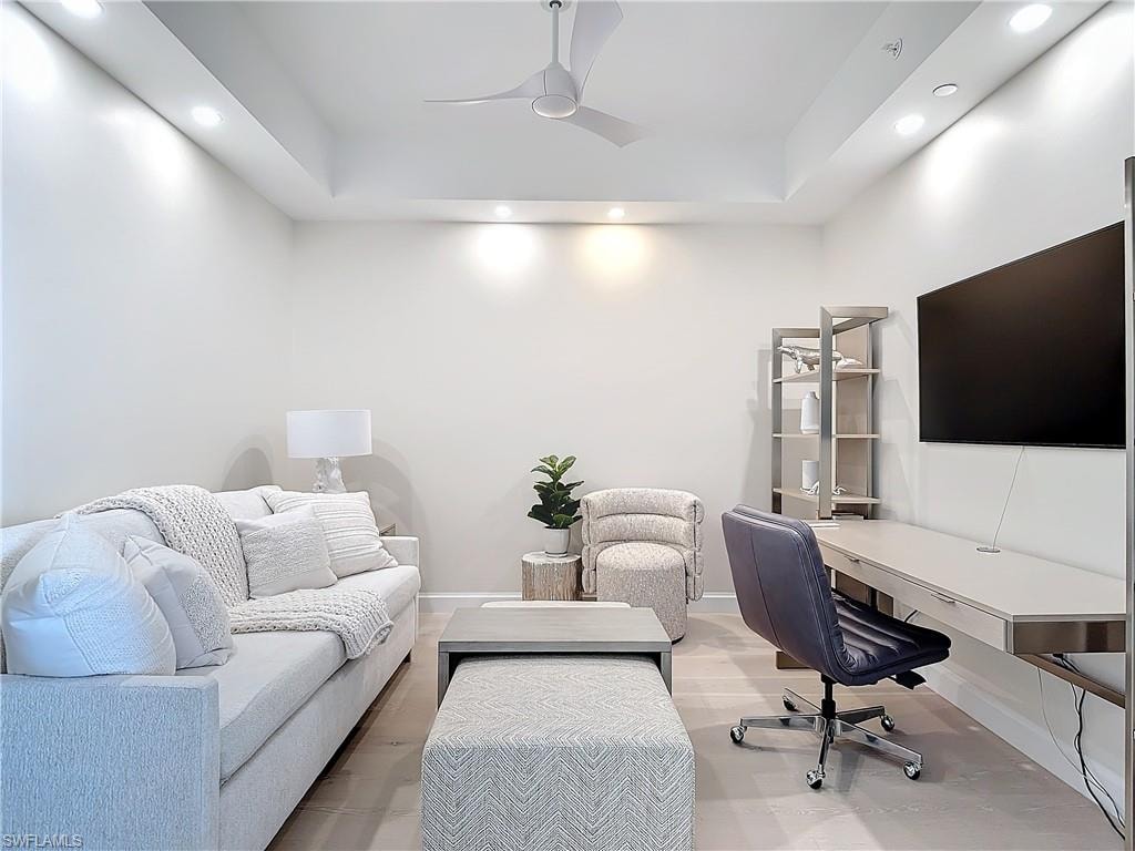 Office with ceiling fan, a raised ceiling, and wood-type flooring
