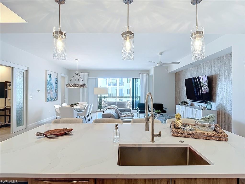 Kitchen featuring a center island with sink, sink, and pendant lighting
