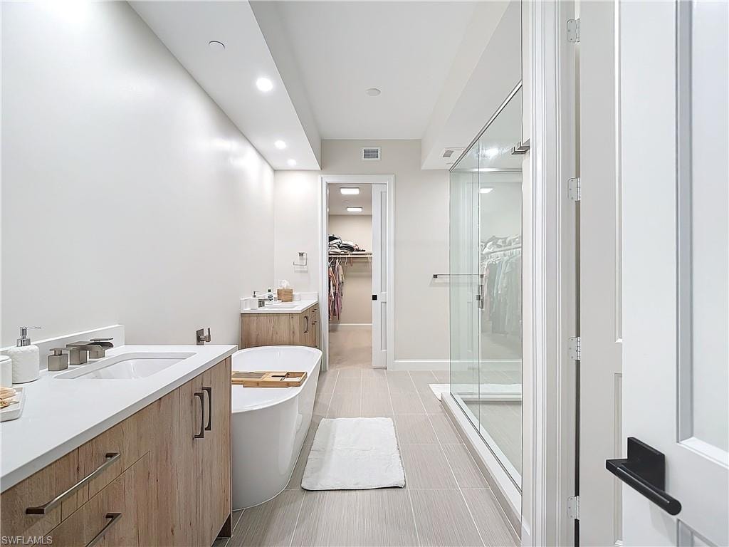Bathroom featuring vanity, shower with separate bathtub, and tile patterned floors