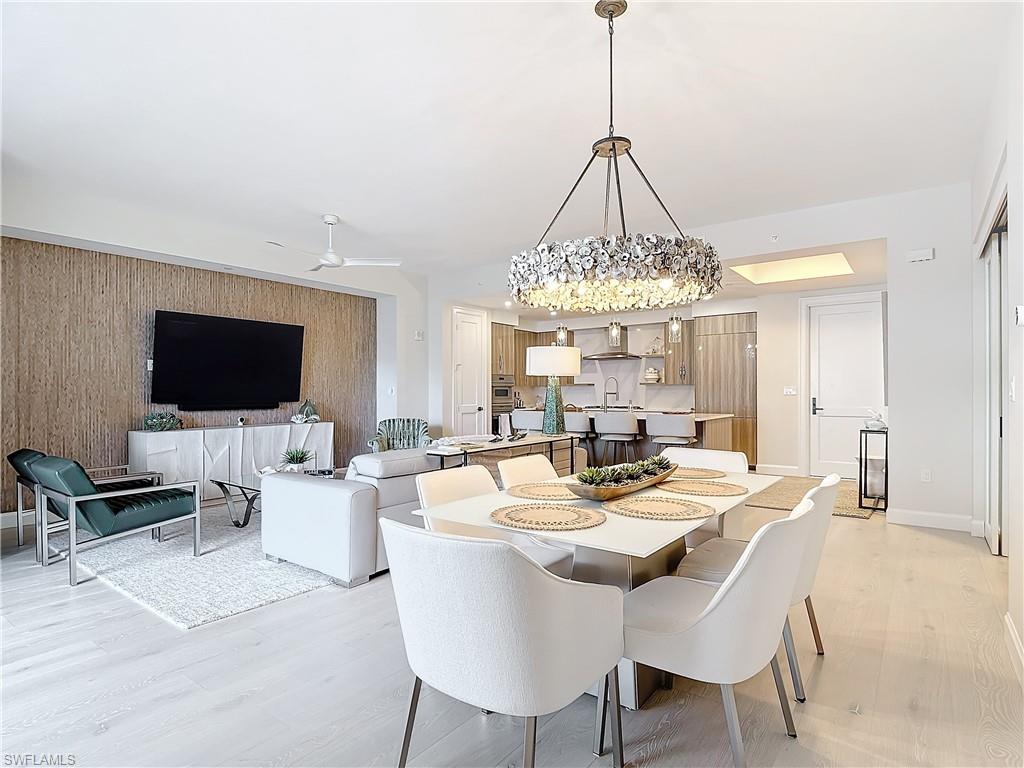 Dining room featuring light hardwood / wood-style flooring, sink, and ceiling fan with notable chandelier