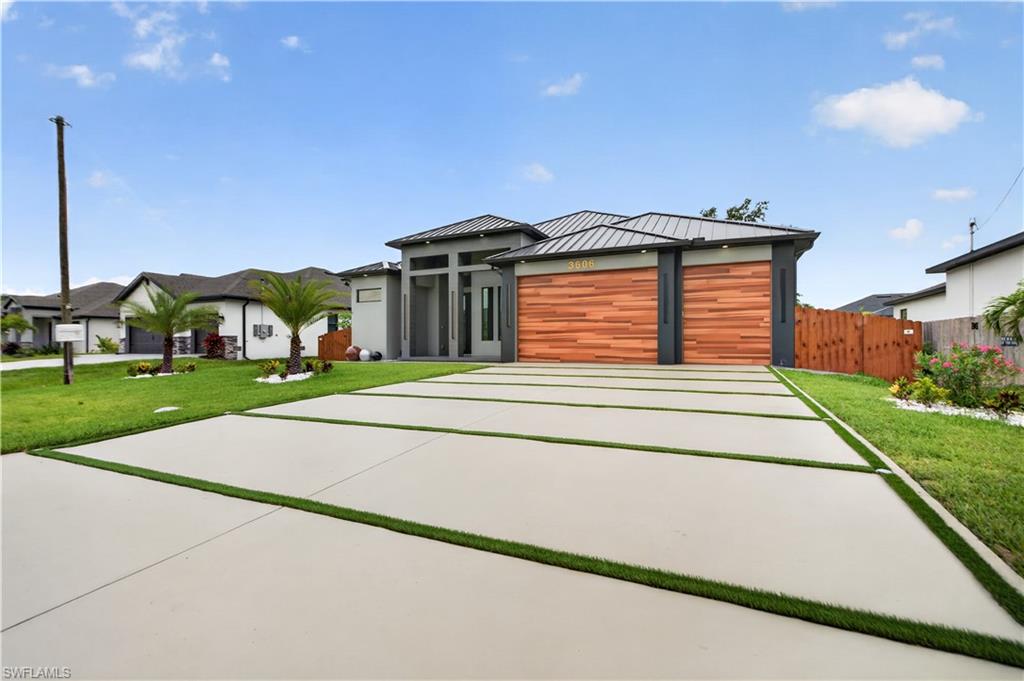 Contemporary exterior featuring a metal roof and a patterned concrete driveway with artificial turf accents