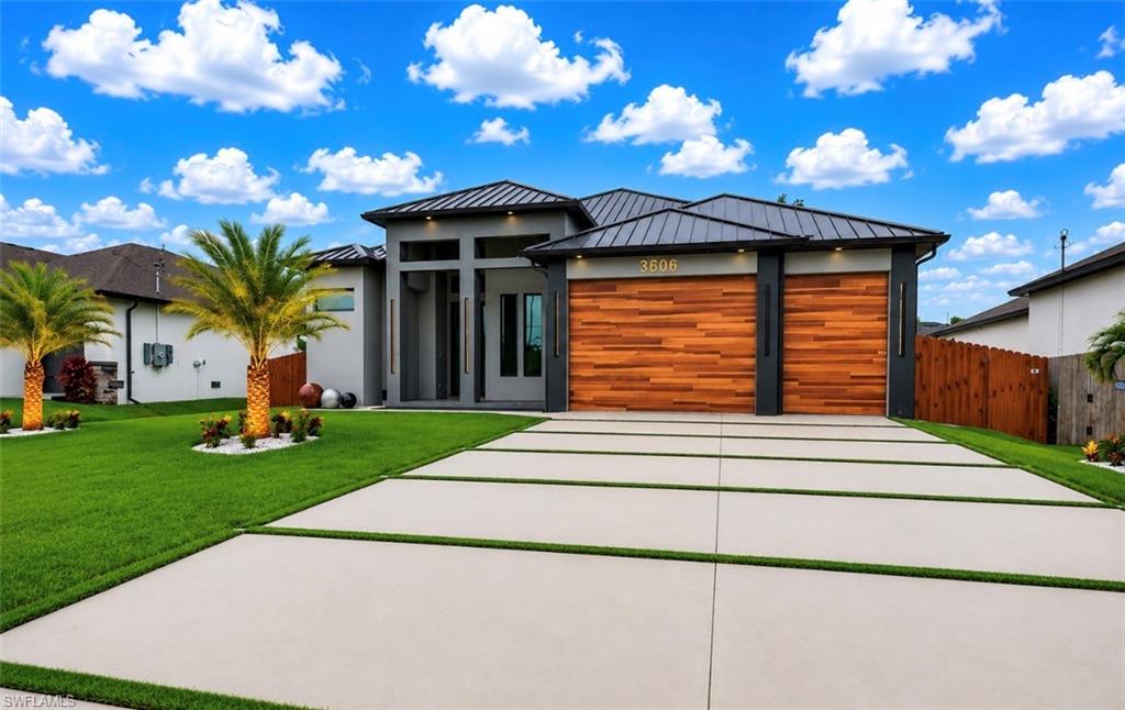 Modern exterior featuring a dark metal roof, wood-finish garage doors, and a decorative front entry
