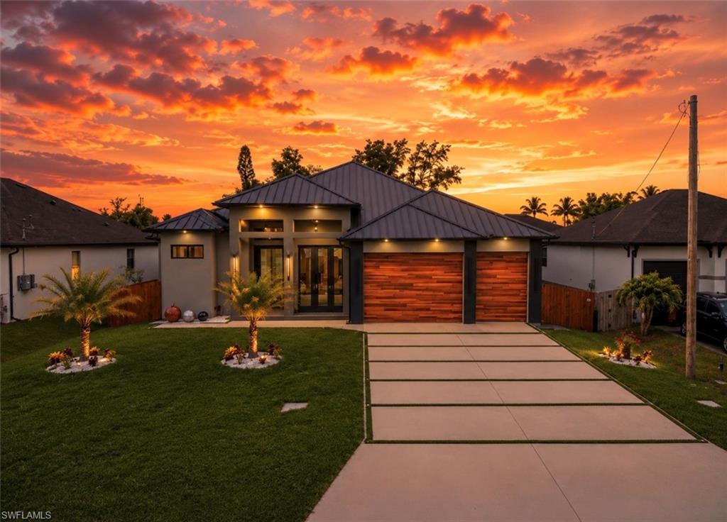 Contemporary exterior featuring a dark metal roof, wood-finish garage doors, and a segmented concrete driveway