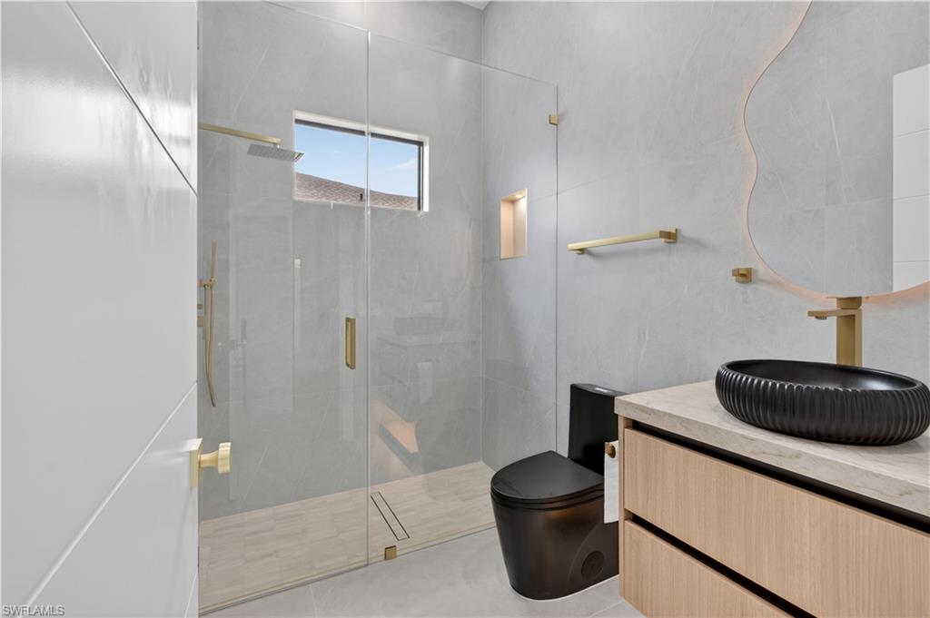 Glass-enclosed shower with a rainfall showerhead and handheld sprayer