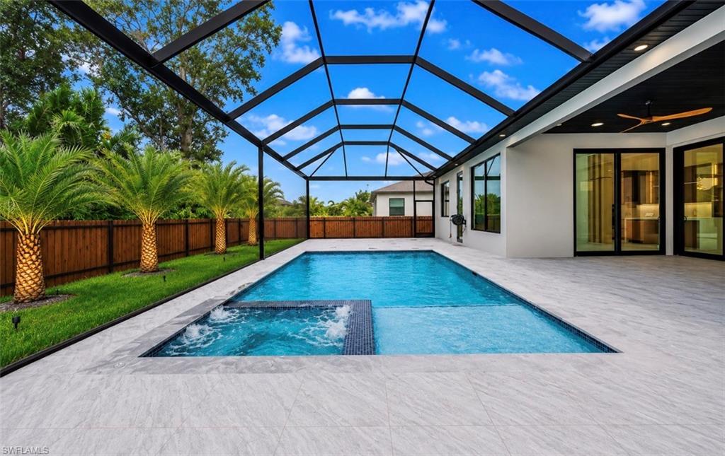 Screened lanai featuring a swimming pool and attached spa, surrounded by large format tile decking