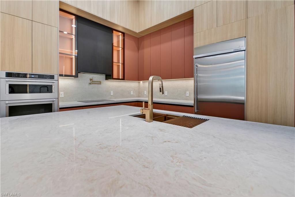 Expansive kitchen island with a stone countertop and an undermount sink with a bronze-finish faucet