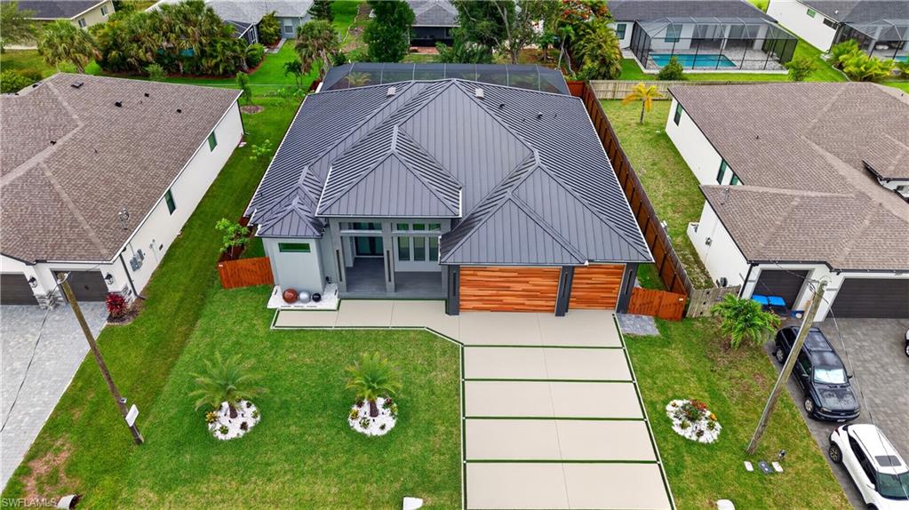 Contemporary residence featuring a dark metal roof, a multi-panel front door, and wood-finish garage doors
